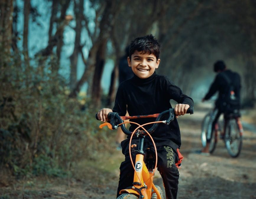 boy in black long sleeved shirt riding orange bicycle